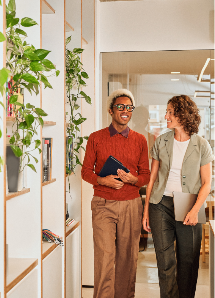 Two people walking through an office and talking 