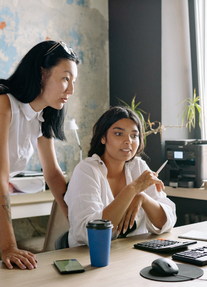 Two women talking whilst looking at their computer in an office 