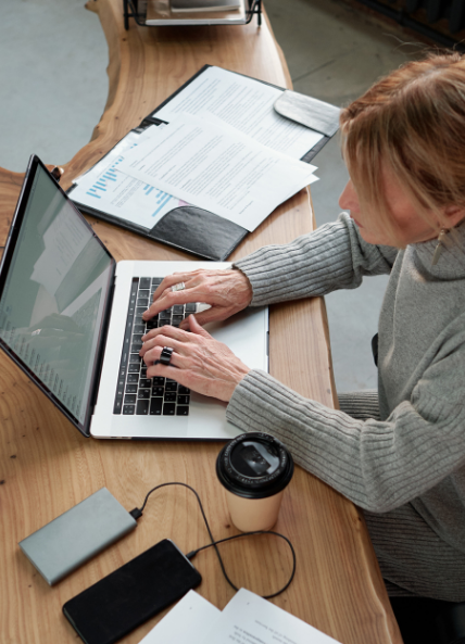 Women working on a laptop with coffee cup and papers beside her