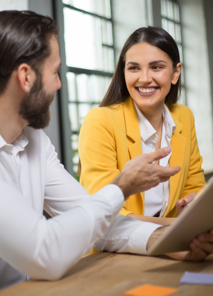 Image of man and women smiling at work with an ipad