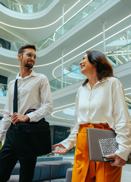 One man and one women walking through the office and talking 