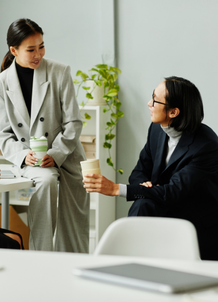 Two people talking in an office environment with coffee cups 