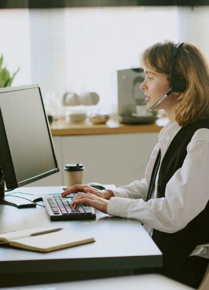 A women working on a computer in the office and speaking on the telephone